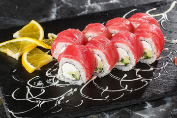Sushi Rolls with cucumber, tuna, and Cream Cheese inside on black slate isolated on black marble background. Philadelphia roll sushi with shrimp. Sushi menu. Horizontal photo.