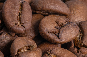 Enlarged roasted coffee beans, prepared for grinding in a grinder and brewing. Fresh, aromatic coffee in the morning.