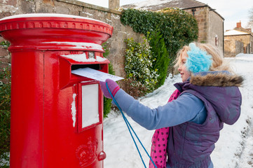 Young girl in a snow covered scene posting her letter to Santa