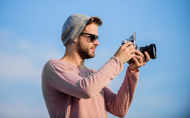 Manual settings. Photojournalist concept. Travel blogger. Professional photographer. Handsome photographer guy retro camera. Guy photographer outdoors sky background. Hipster reporter taking photo