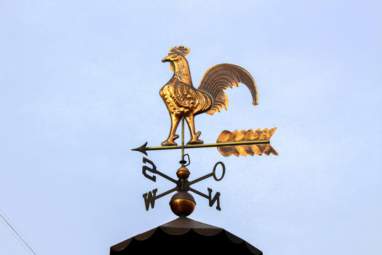 Nice weathercock on a roof with blue sky background