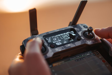 Young man are holding his drone controller in army skin.