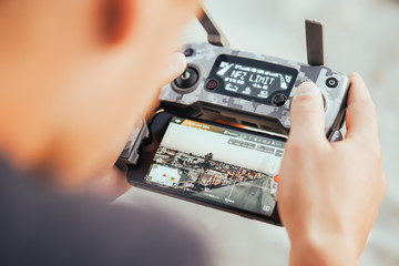 Young man are holding his drone controller in army skin.