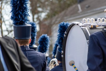 A high school marching band performs during a Veterans Day parade. Photo taken from the back and...
