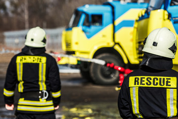 Group of firefighters  in safe helmet and uniform standing by car