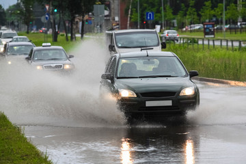 Driving car on flooded road during flood caused by torrential rains. Cars float on water, flooding...