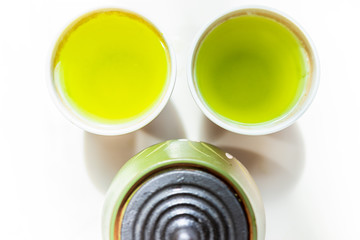 Closeup flat top of small two cups filled with Japanese vibrant green yellow sencha fukamushi or genmaicha tea color for breakfast or ceremony
