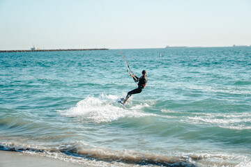 Professional kiter rides on the waves, jumps on the sea.