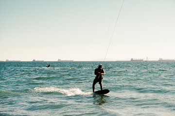 Professional kiter rides on the waves, jumps on the sea.