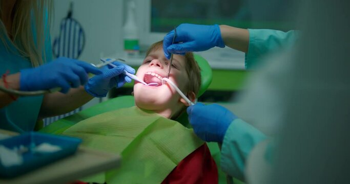 Slow motion child in dentist chair having dental checkup. Dentist using drill on child's teeth.