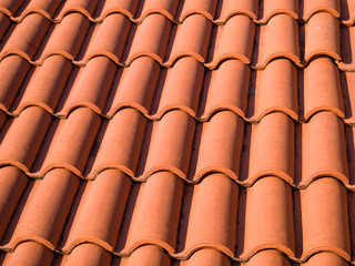 Closeup of the red clay roof tiles. Shingles. Old and used overlapping red classic style roofing...