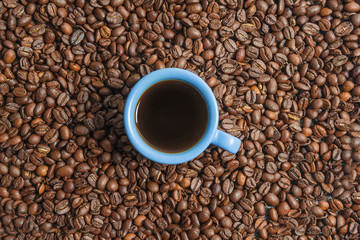 Coffee break concept. One blue cup of coffee on the roasted coffee beans background. Copy space, flat lay