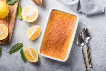 Homemade casserole, pudding, cheesecake, tart, pie or mousse with Fresh lemons and leaves on grey...
