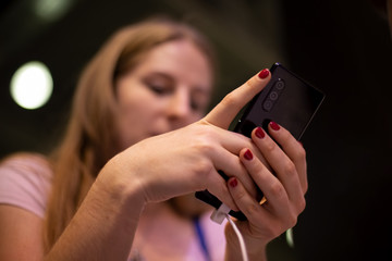 aa young blonde woman holds mobile phone in hands and looks into it. close up, soft focus