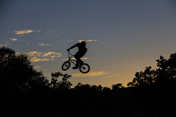 Bmx cyclist jumping in sunset evening