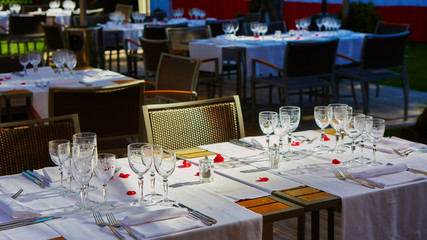 Fine dining table setting with white china and wine and water crystal glasses, with silverware in the order of use, and romantic red tablecloth ready for guests at an event, wedding or at a restaurant