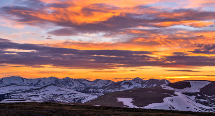 Fototapeta na wymiar Sunset Spring Rockies - A panoramic view of colorful Spring sunset clouds over Trail Ridge Road and snow-capped high peaks of the Continental Divide at top of Rocky Mountain National Park, CO, USA.