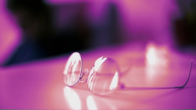 Modern titanium eyewear glasses on the table with purple colored background 