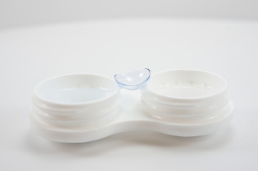 container for soft contact lenses and lens on light background