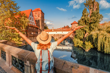 Happy asian woman tourist enjoying sunset view of the old town of Nurnberg city and Pegnitz river....