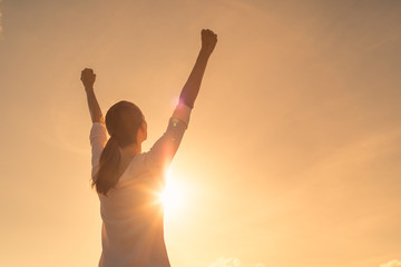 Strong young woman with arms up to the sky. People winning and victory concept.