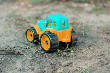 Toy plastic tractor in the garden. Toy tractor on the ground