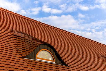 red tile roof with window and blue sky