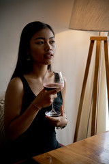 Asian girl in a cafe. Beautiful Balinese women with glass of wine with window reflection
