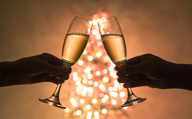 Two people enjoying champagne next to Christmas tree. Holiday celebration  concept. 