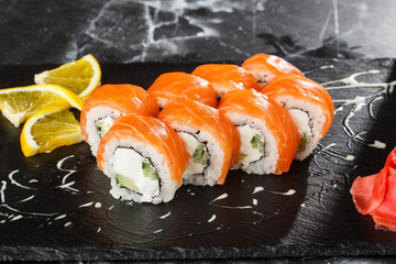 Sushi Rolls with cucumber, avocado, salmon and Cream Cheese inside on black slate isolated on black marble background. Philadelphia roll sushi. Sushi menu. Horizontal photo.