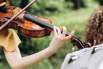 female musician performs at an outdoor wedding. Curl with the neck of the violin closeup. The actor...
