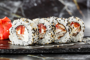 Sushi Rolls with tomato, eel, crab meat and cream cheese inside on black slate isolated on black marble background.  rolls covered black tobiko or masago caviar. Sushi menu. Horizontal photo.