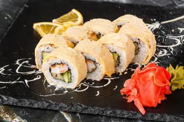 Sushi Rolls with avocado, eel, cucumber and cream cheese inside on black slate isolated on black marble background. California rolls covered on omelet Sushi menu. Horizontal photo.