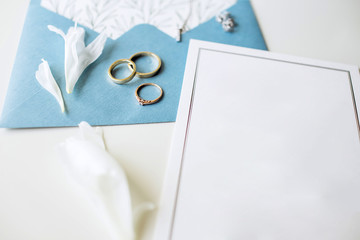 Luxury set of wedding invitations, wedding rings, elegant accessories of the bride on a white background. Blue paper envelope for invitation.