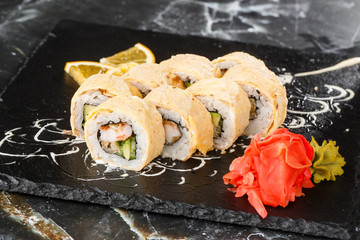 Sushi Rolls with avocado, eel, cucumber and cream cheese inside on black slate isolated on black marble background. California rolls covered on omelet Sushi menu. Horizontal photo.