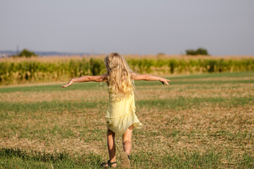 wild dance of happy child in rural path in yellow dress