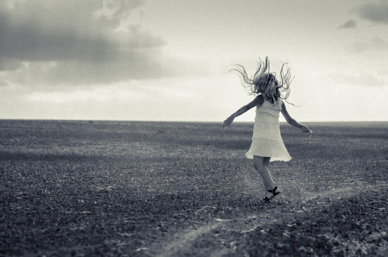 strange image of girl dancing in the field with hair flying in the air