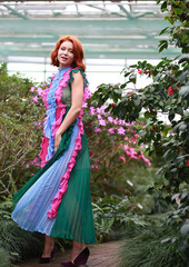 Obraz na płótnie Canvas beautiful red-haired girl in arranger where azalea blooms in a colorful flying dress
