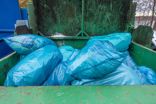 in a garbage compactor there are many blue garbage bags to be pressed together