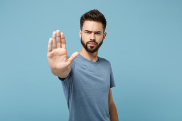 Young displeased serious man in casual clothes posing isolated on blue wall background, studio portrait. People sincere emotions lifestyle concept. Mock up copy space. Showing stop gesture with palm.