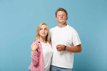 Fototapeta premium Young fun couple two friends guy girl in white pink empty blank design t-shirts posing isolated on pastel blue background studio portrait. People lifestyle concept. Mock up copy space. Looking camera.