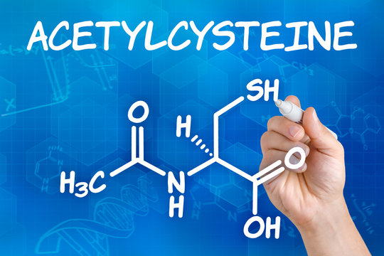 Hand with pen drawing the chemical formula of acetylcysteine