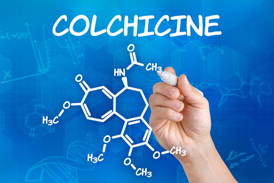 Hand with pen drawing the chemical formula of colchicine