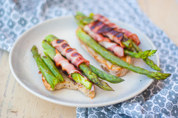 Grilled asparagus with bacon and slice of whole grain bread