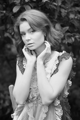 Naklejka premium stunning black and white portrait beautiful young model girl in arranger where azalea blooms in a flying dress. Beauty and Fashion