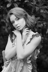 Naklejka premium stunning black and white portrait beautiful young model girl in arranger where azalea blooms in a flying dress. Beauty and Fashion