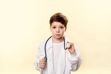 Adorable future doctor a over white background. A boy plays a doctor. children's games. little doctor. white coat and phonendoscope. Emotional baby In a studio