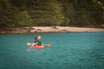 Couple canoeing or kayaking at sea island, Thailand.