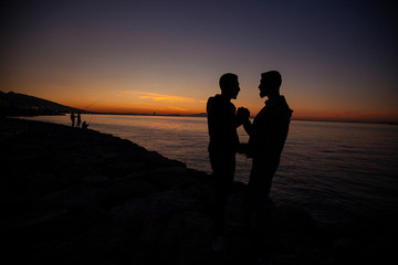Fototapeta na wymiar The couple jumping on the seaside on the sunset background
