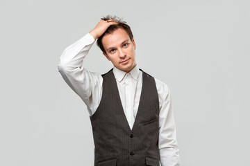 Tired young business man holding hand on head covering face isolated over grey nackground.